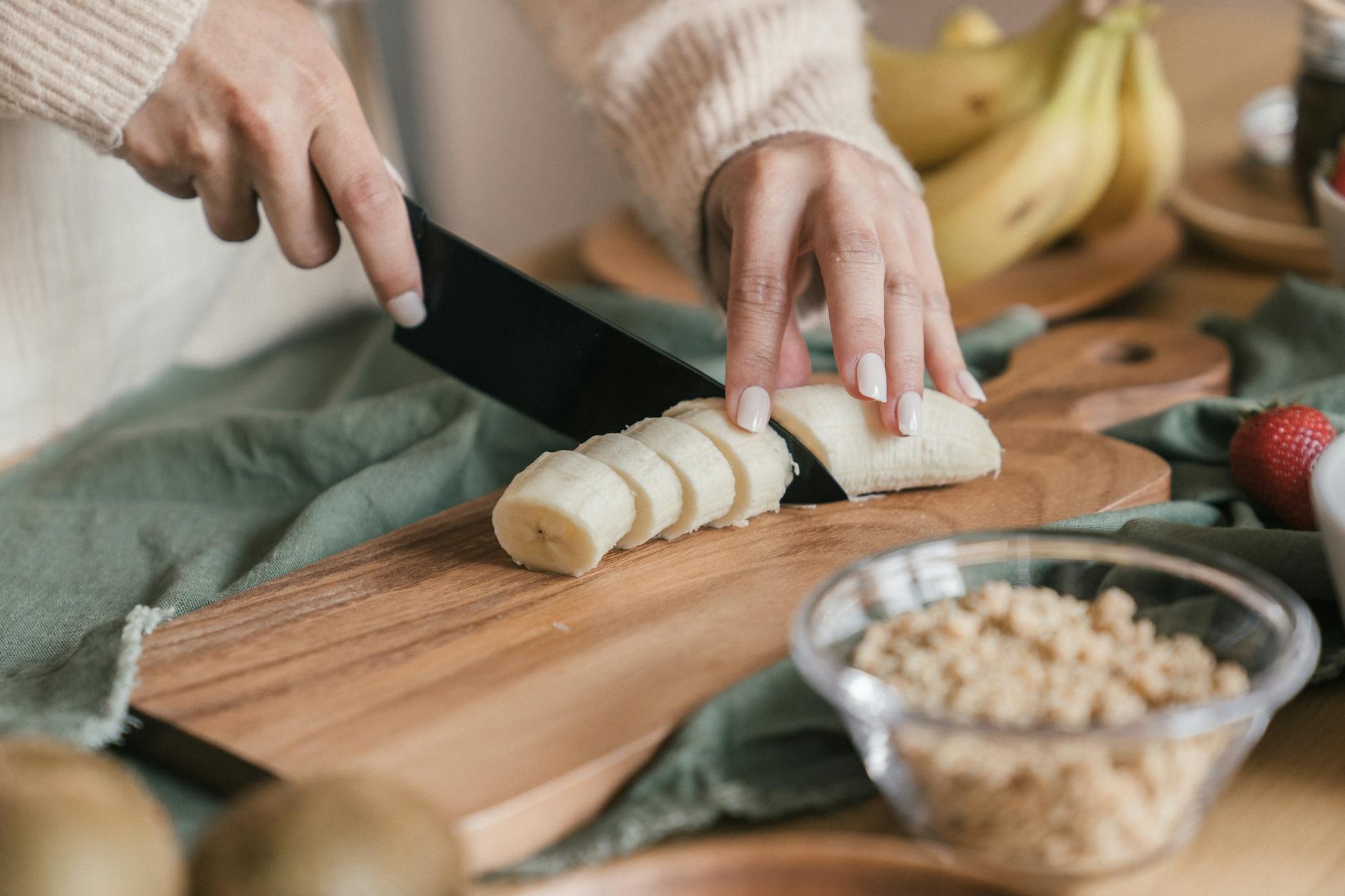 a person cutting a banana on a chopping board