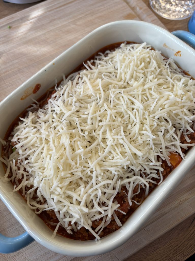 Garniert wird die Low Carb Zucchini-Lasagne mit Reibekäse - und ab in den Ofen.
