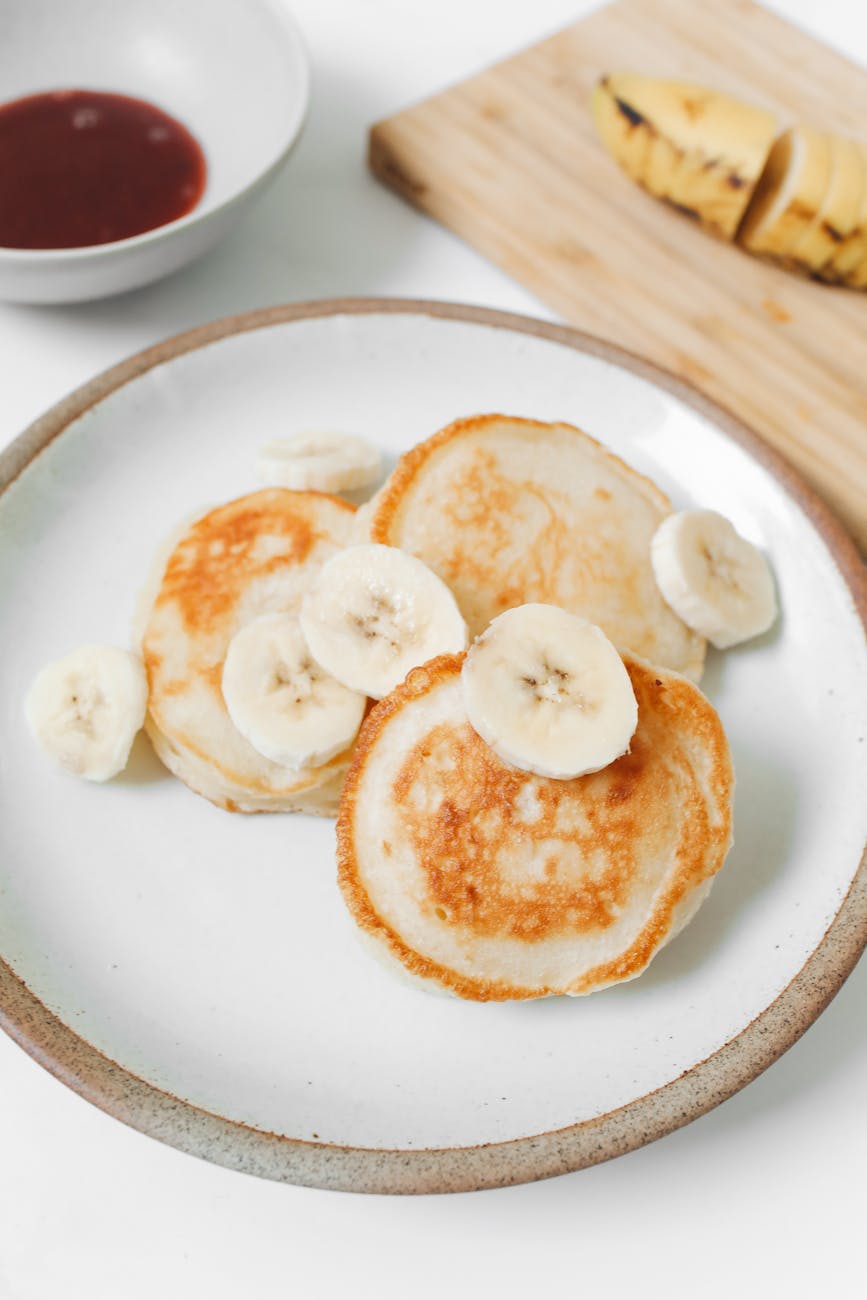 photo of pancakes with banana on white ceramic plate