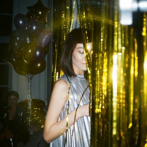 woman hiding behind gold foil curtain