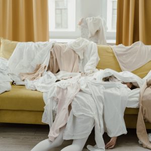 woman lying at the couch covered with clothes