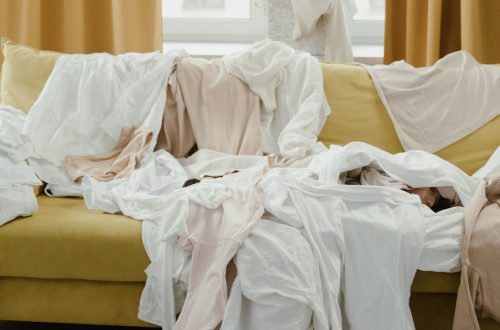 woman lying at the couch covered with clothes