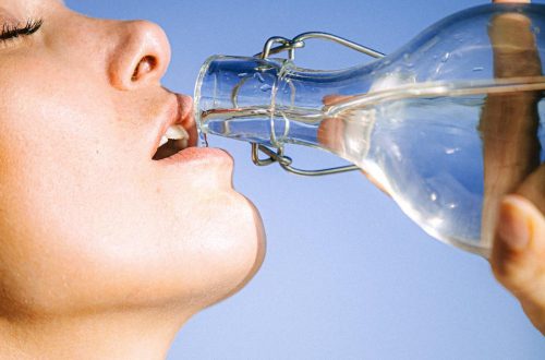 woman drinking water from glass bottle